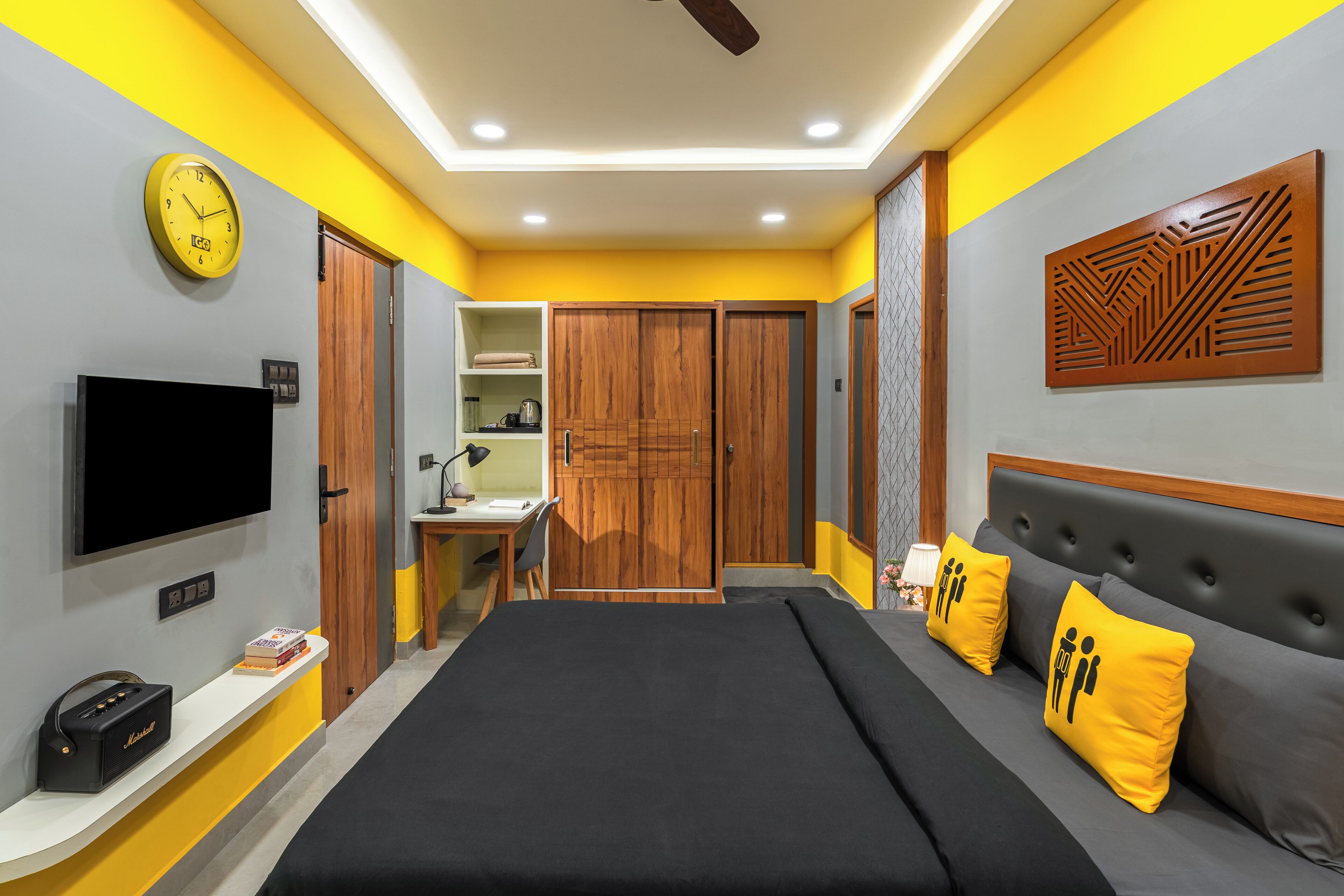 A bedroom with a bed, bedside table, TV, wardrobe, and a mirror.