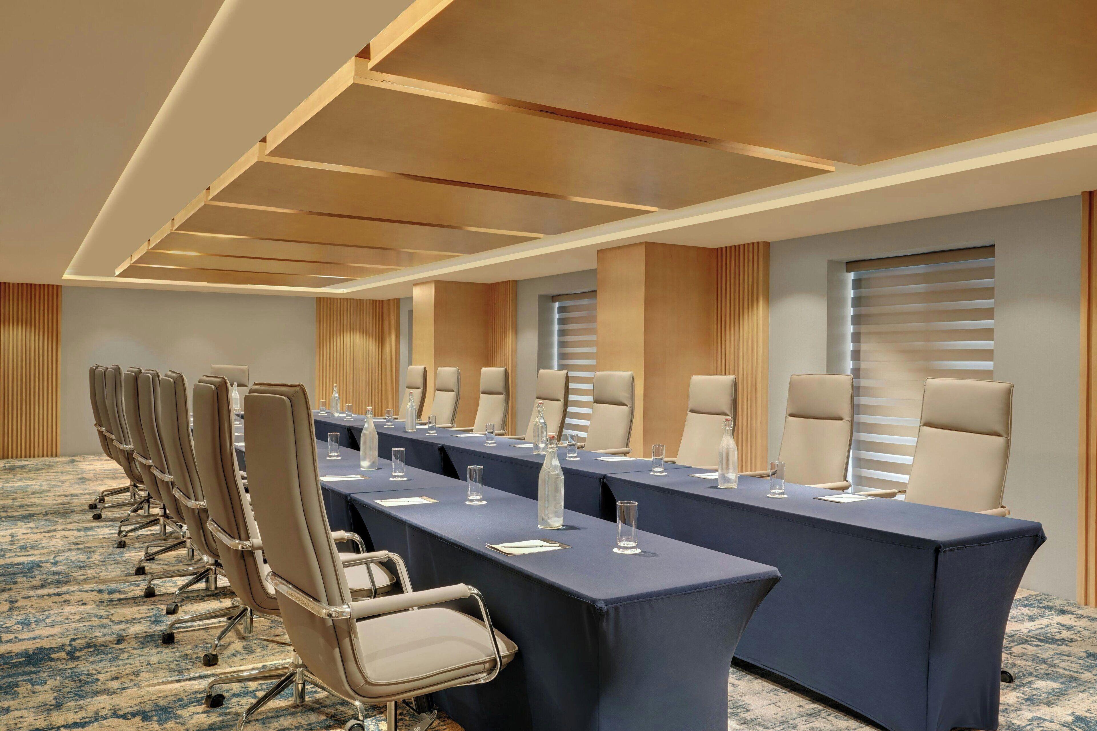 A conference room with a long table, multiple chairs, and a carpeted floor.