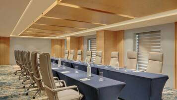 A conference room with a long table, multiple chairs, and a carpeted floor.