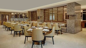 A spacious dining area with multiple tables and chairs, a large bookshelf, and a modern interior design. - The Fern Residency Bengaluru, Seshadripuram, Series by Marriott (Bengaluru)