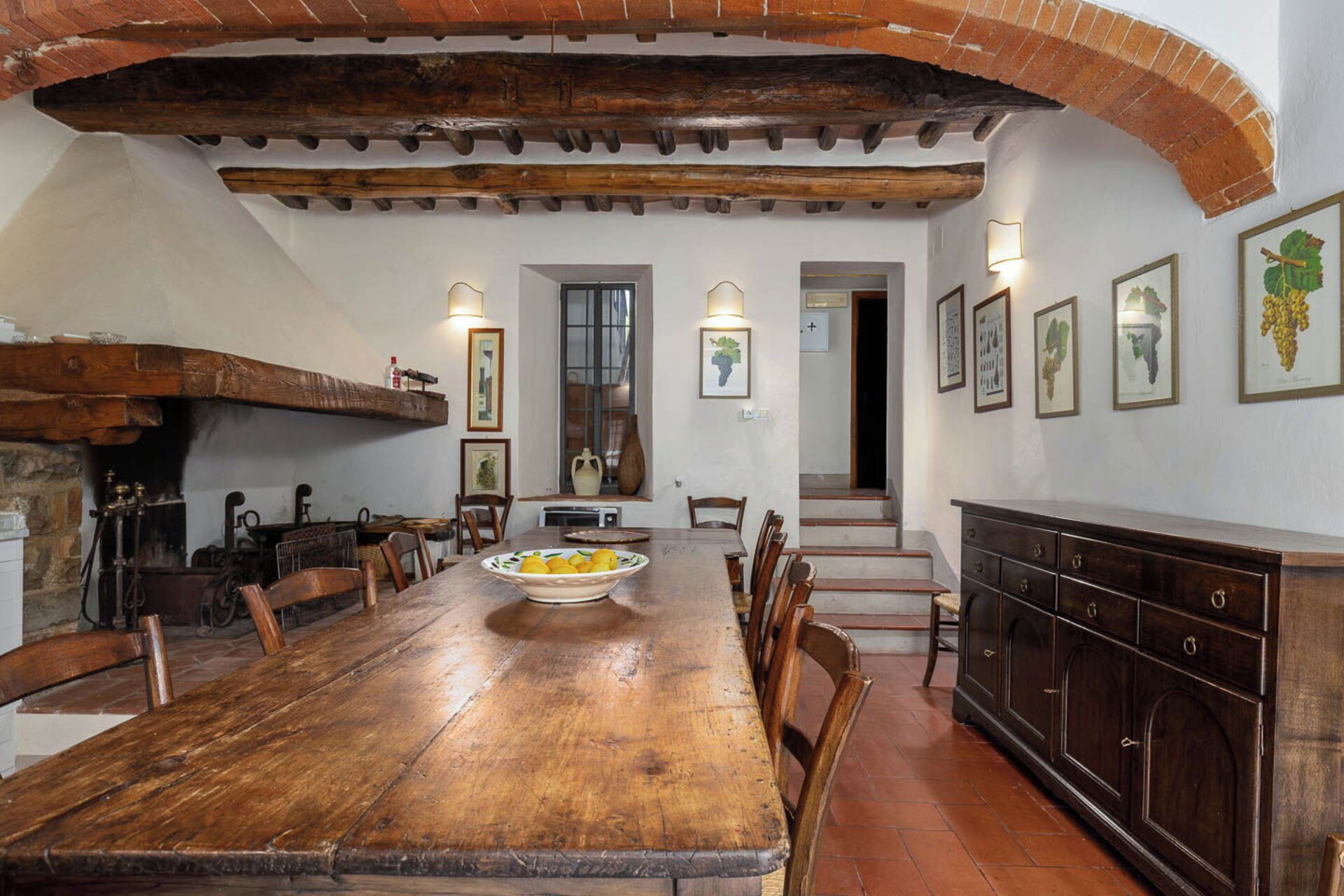 A rustic dining area with a wooden table, chairs, and a brick fireplace.