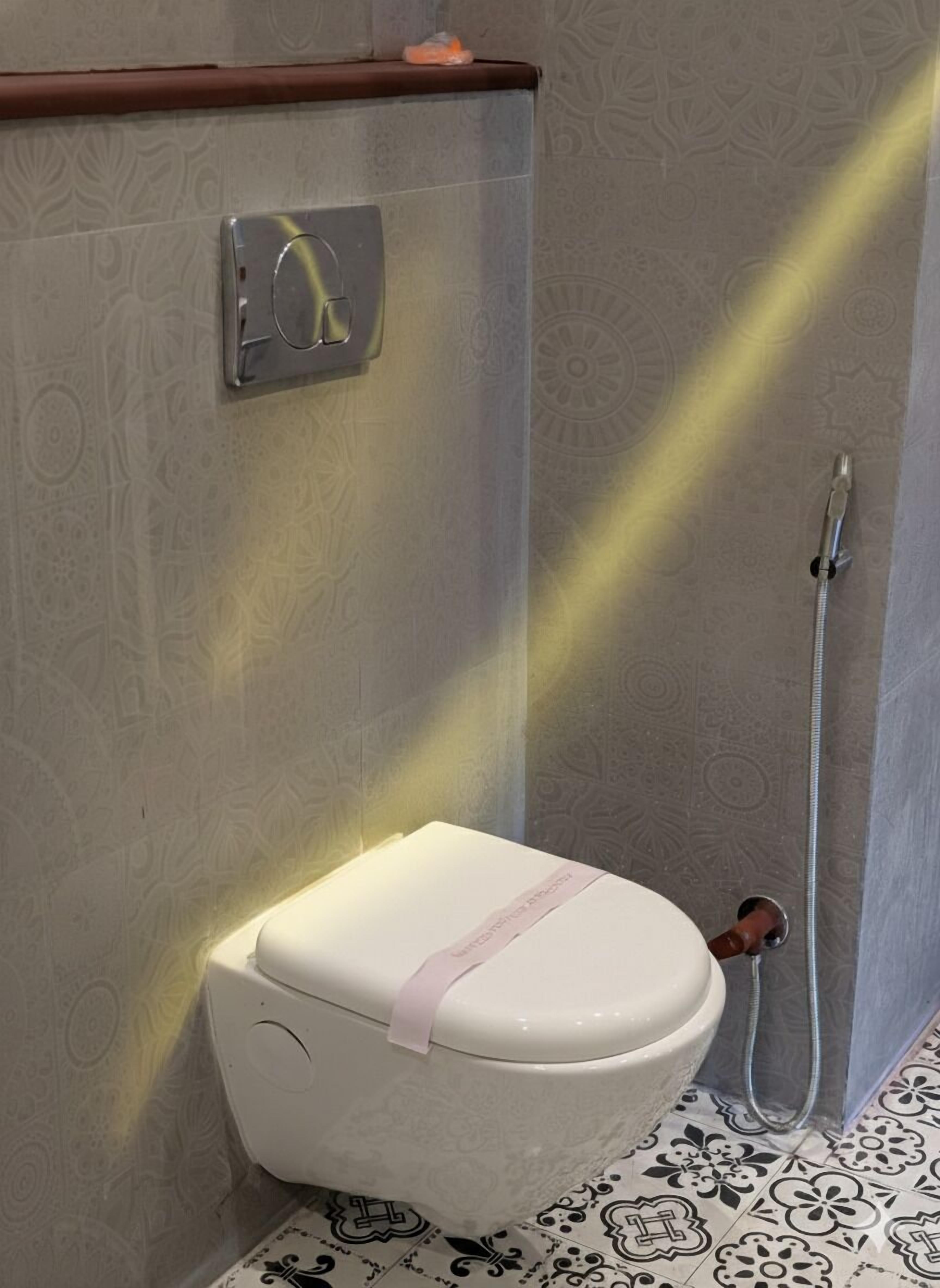 Een badkamer met toilet, douche en betegelde vloer.