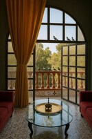 Una habitación con una mesa de vidrio, sofás rojos y vistas a pájaros en un balcón.