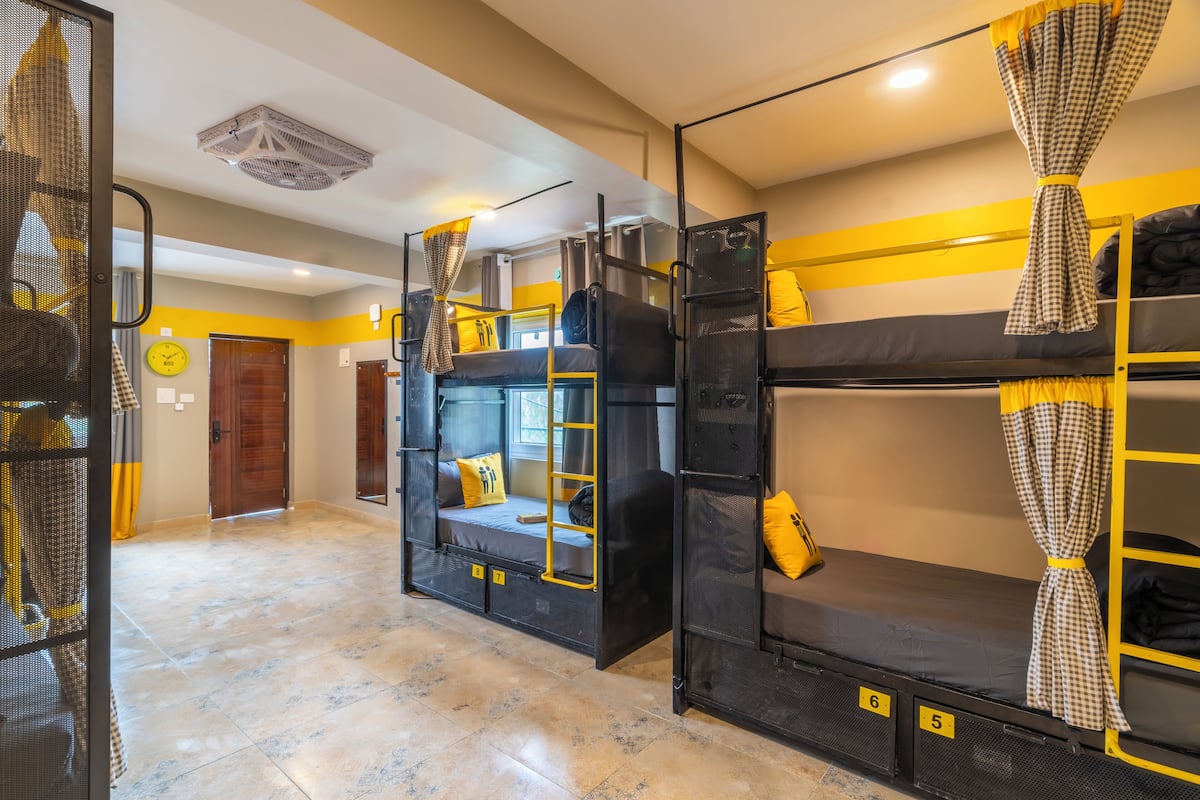 Une chambre d’auberge de jeunesse avec des lits superposés, une échelle et un petit coin salon.