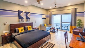 Quarto de hotel com cama, escrivaninha, cadeira e varanda com vista.