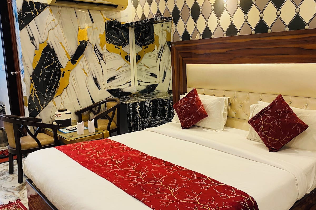 A hotel room with a bed, a nightstand, a chair, and a marble-patterned wall.