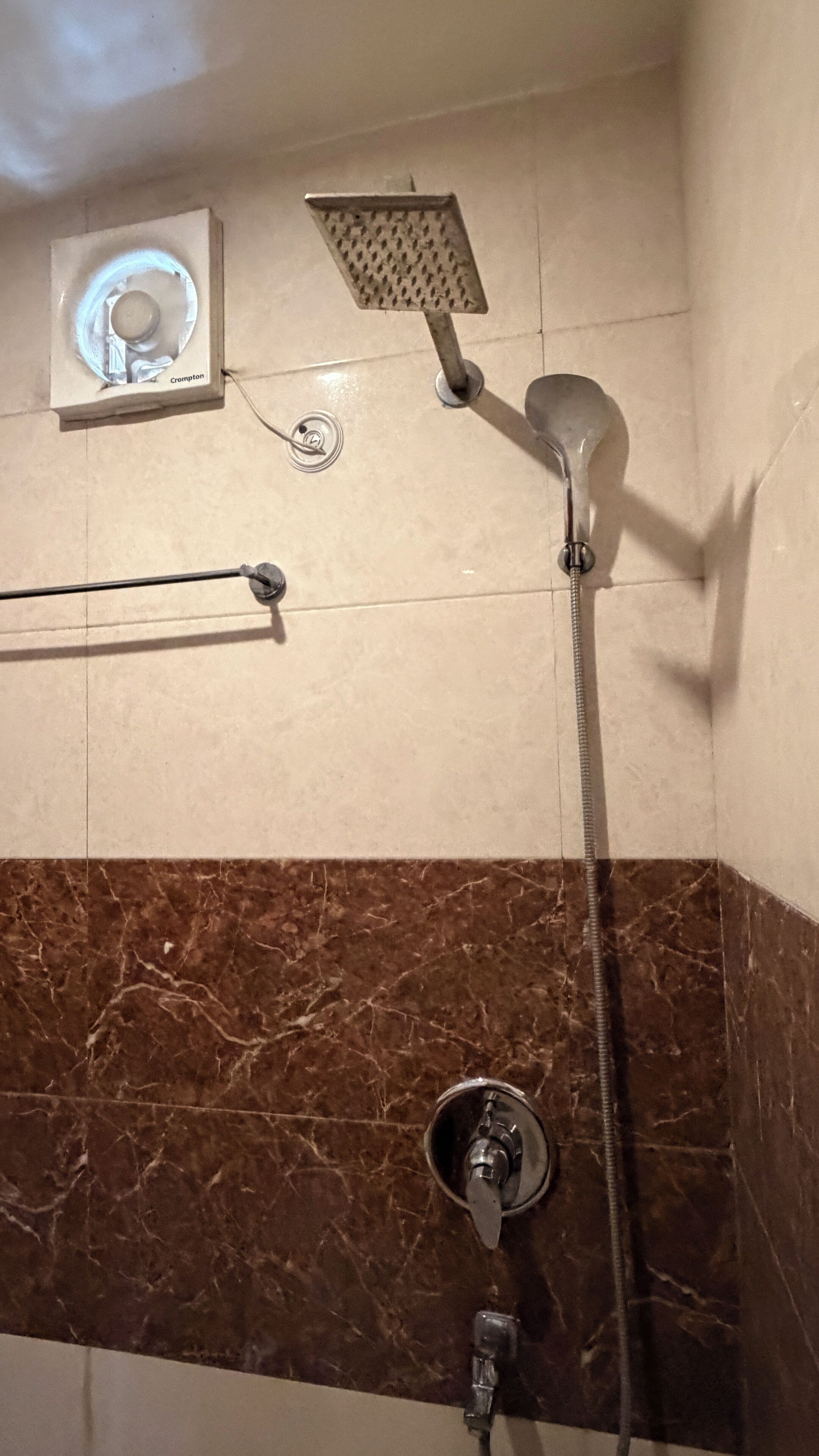A bathroom with a shower, a towel rack, and a wall-mounted air purifier.