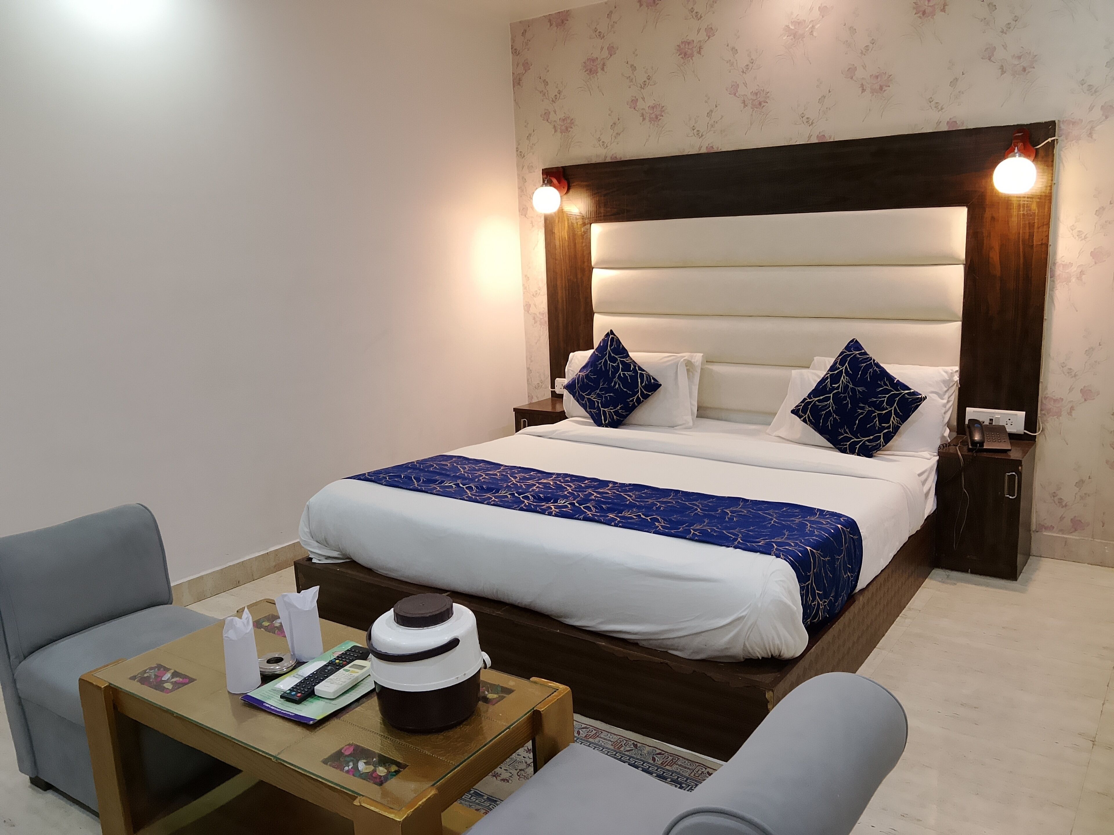 A hotel room with a bed, bedside tables, a desk, and a chair.