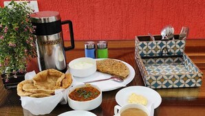 A tray with a variety of food items including bread, soup, and a cup of tea, along with condiments and a thermos. - Hotel The Raj Palace (New Delhi)