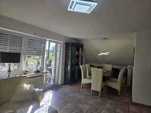 Un amplio salón con una mesa de comedor, sillas, un sofá y un armario.