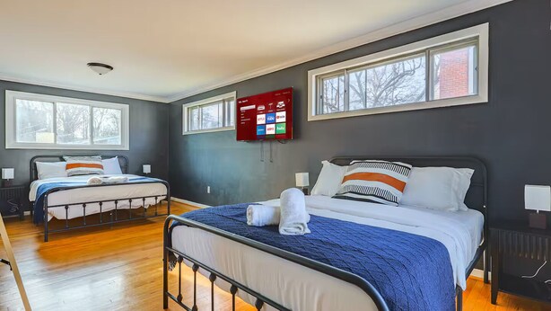 Een hotelkamer met twee bedden, een flatscreen televisie aan de muur en grote ramen.