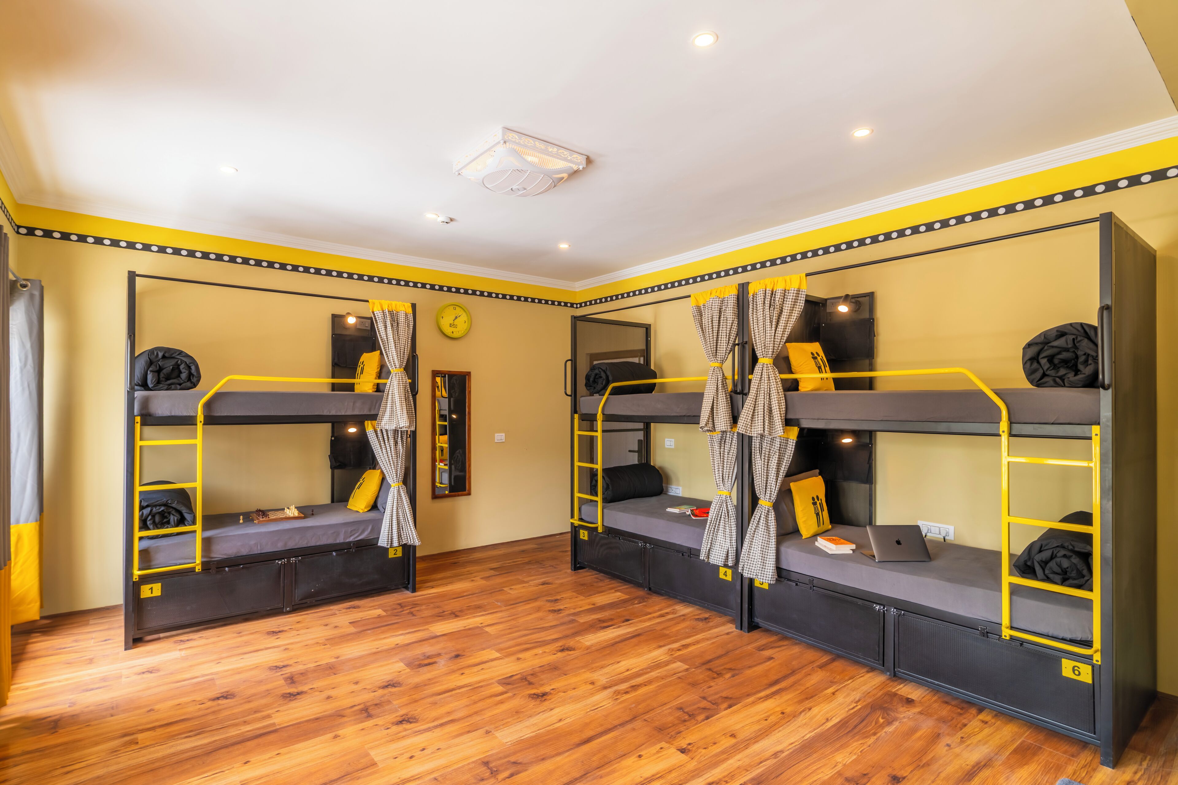A room with bunk beds, wooden flooring, and a clock on the wall.