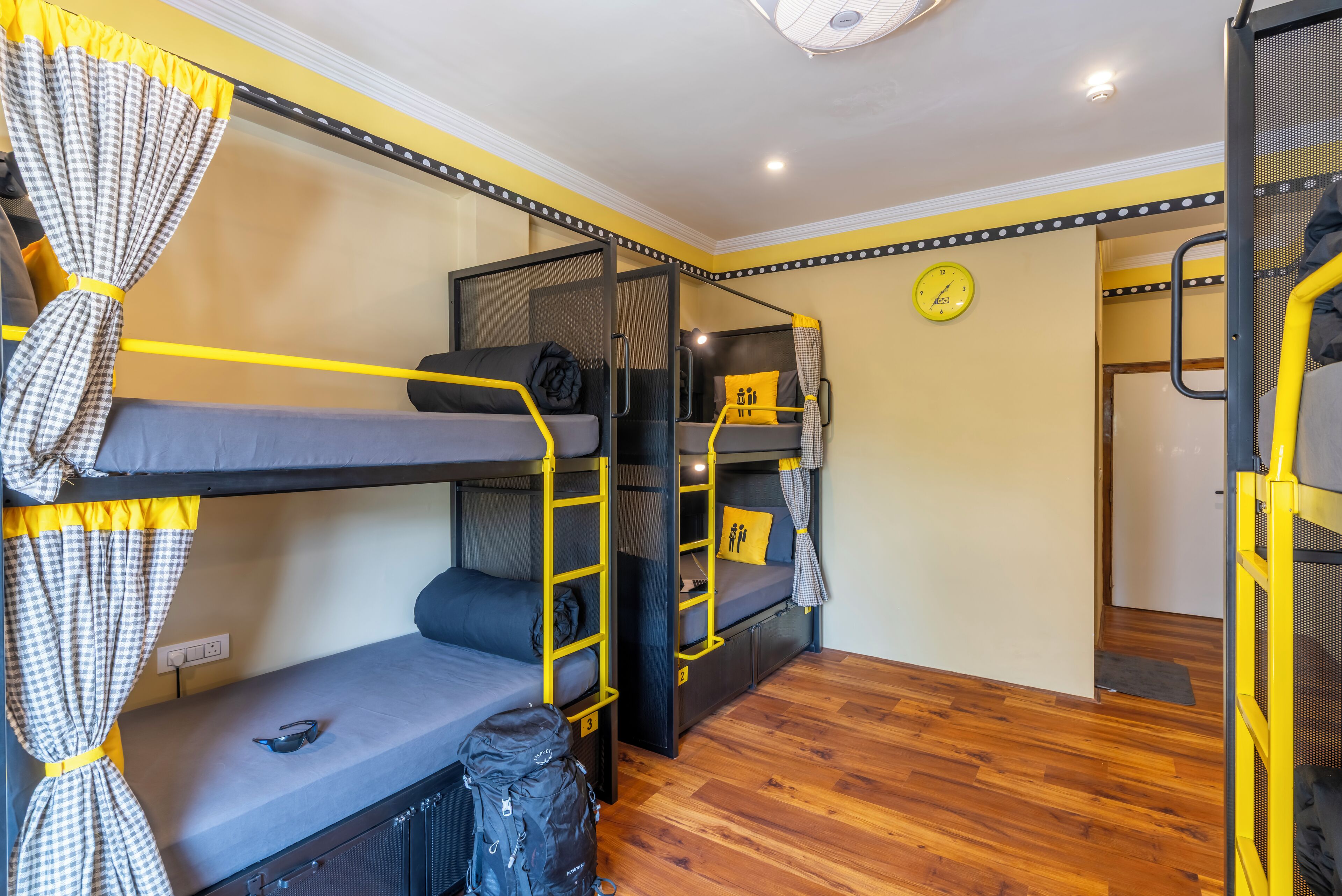 A bunk bed room with a clock on the wall, a suitcase, and a ladder.