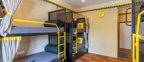 A bunk bed room with a clock on the wall, a suitcase, and a ladder.