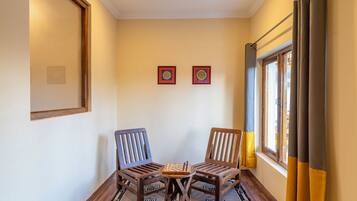 Una habitación con dos sillas de madera, una mesita y dos cuadros enmarcados en la pared.