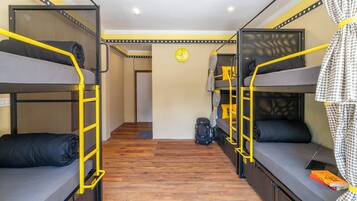 Een slaapkamer met een stapelbed, een houten vloer, een klok aan de muur en een koffer op de vloer.