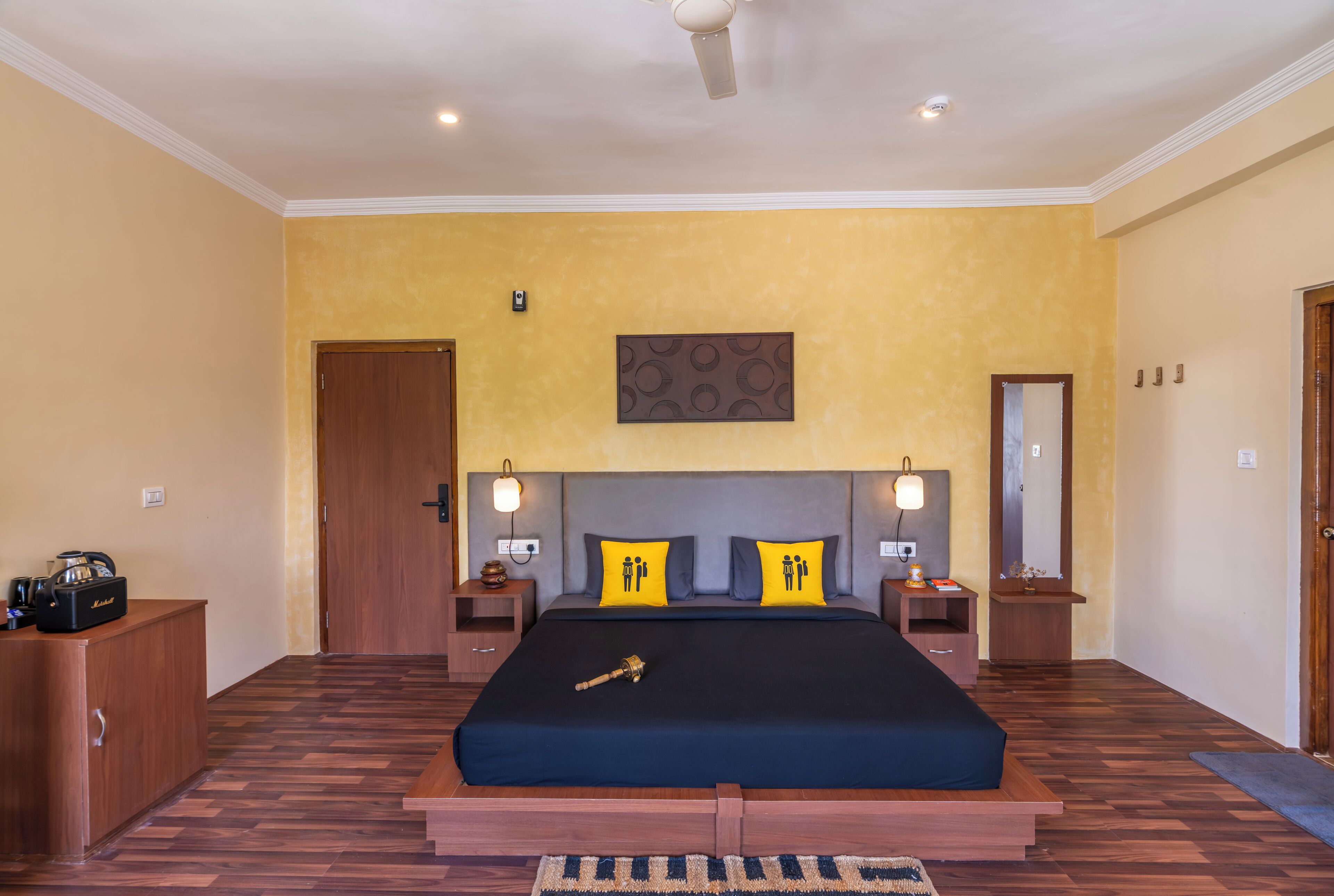 A bedroom with a large bed, wooden headboard, two bedside tables with lamps, a wooden wardrobe, and a ceiling fan.