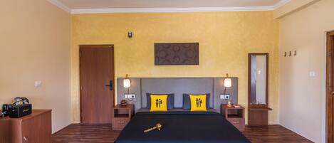 A bedroom with a large bed, wooden headboard, two bedside tables with lamps, a wooden wardrobe, and a ceiling fan.