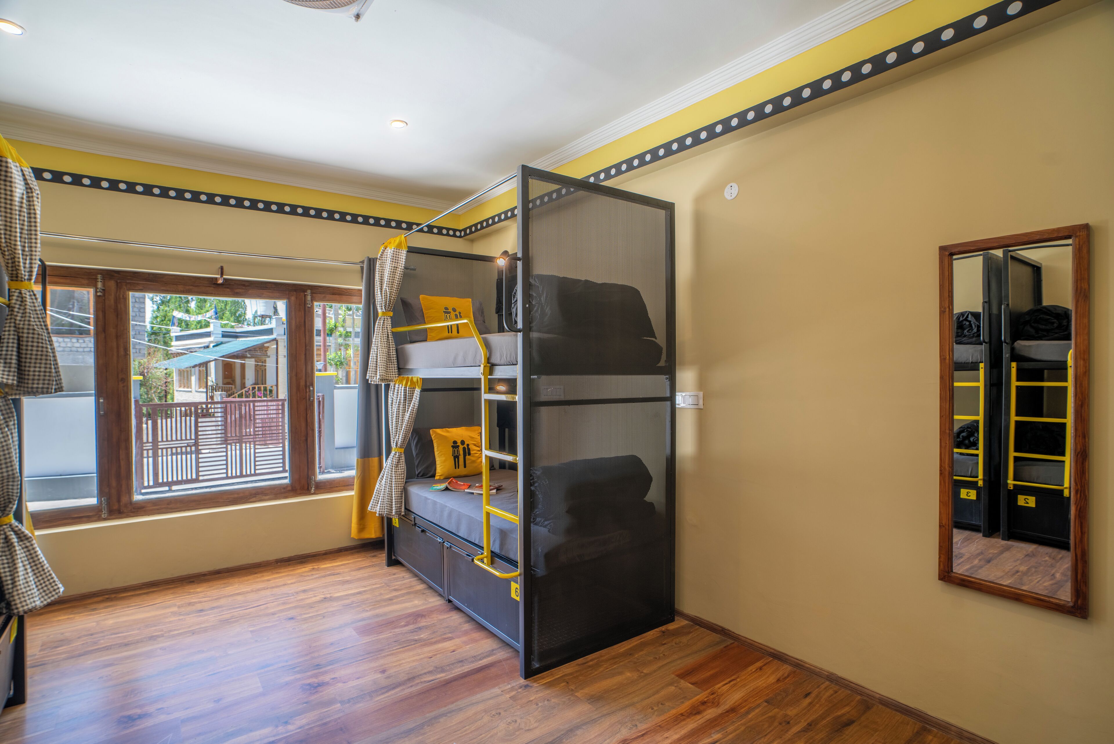 Une chambre avec un lit superposé, une fenêtre donnant sur un paysage agréable, un miroir et une porte.