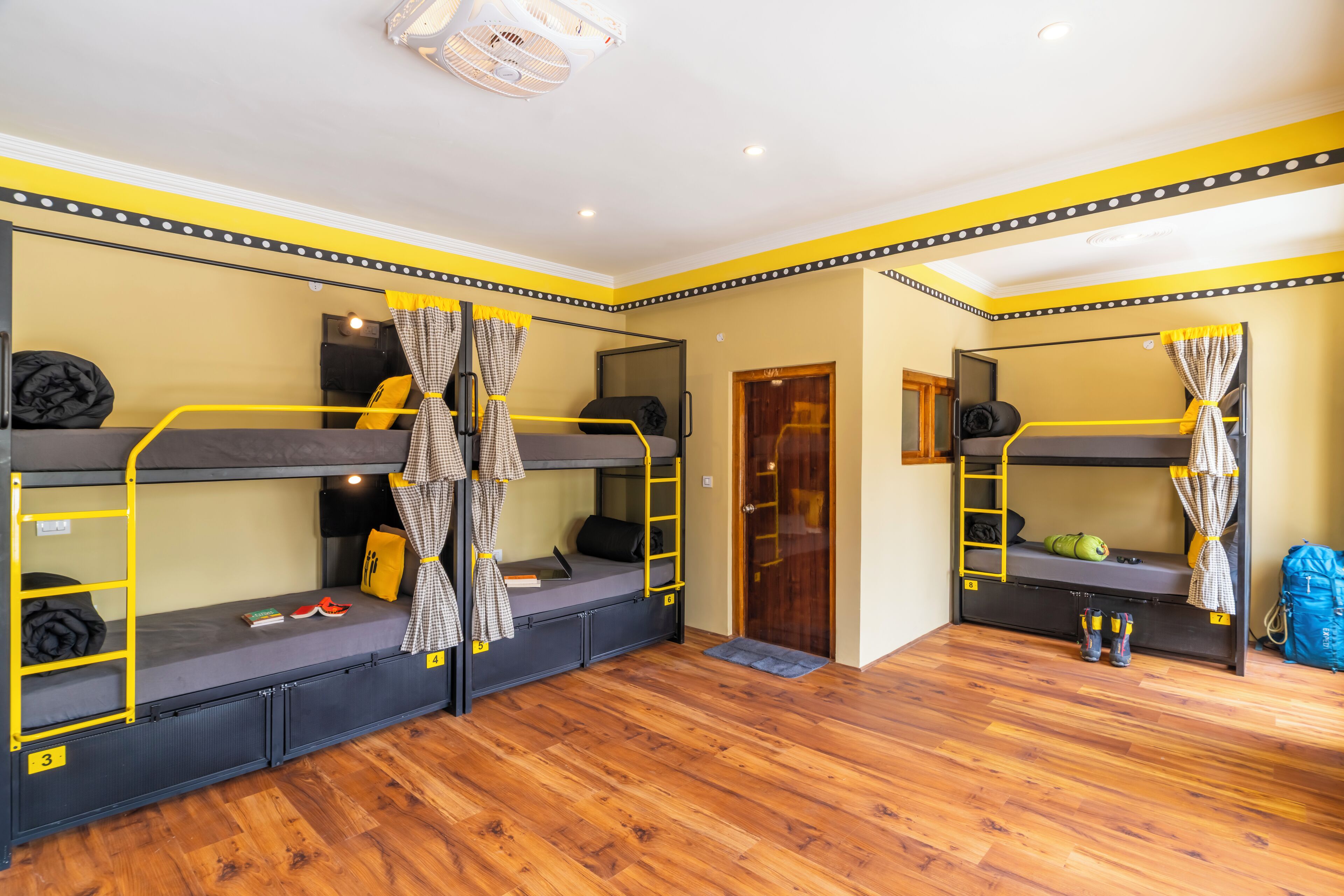 Una habitación con literas, piso de madera y una puerta.