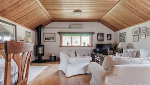 A cozy living room with a fireplace, white sofas, and a television. - A house by the forest with a stream and plenty of peace and quiet (Stenis)