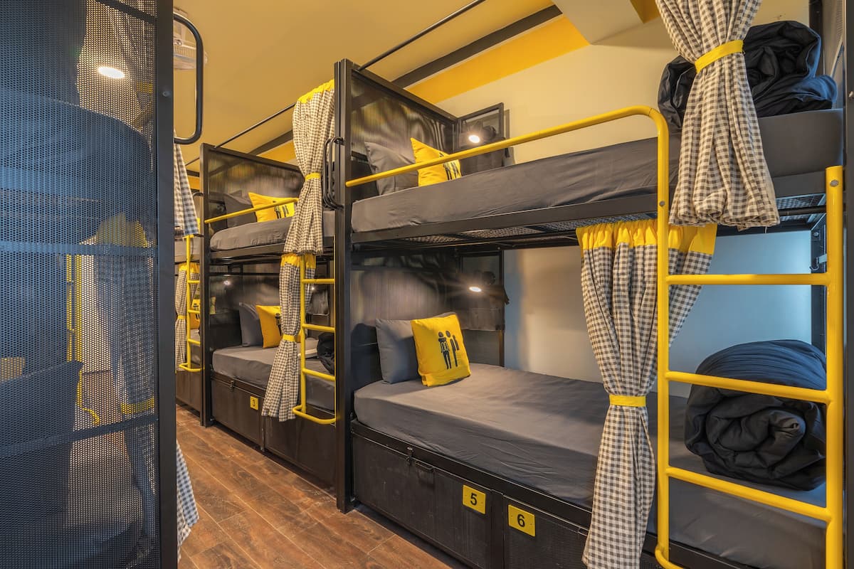 A bunk bed room with a checkered curtain, a yellow pillow, and a number on the side.