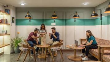 A group of people playing a game of Jenga in a room with green and white walls, wooden furniture, and pendant lighting.