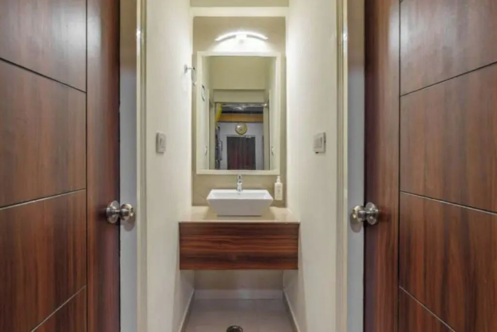 A narrow hallway leading to a bathroom with a sink and mirror.