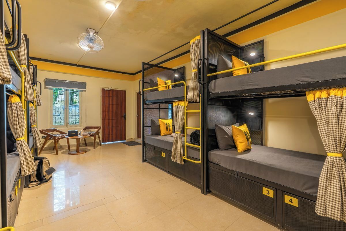 A dormitory-style room with bunk beds, a desk, and a chair.