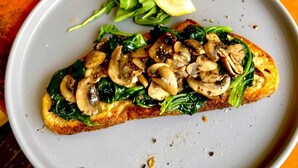 A plate with a slice of bread topped with mushrooms and spinach, accompanied by a slice of lemon and a small side salad. - The Deck Toul Tompoung (Phnom Penh)