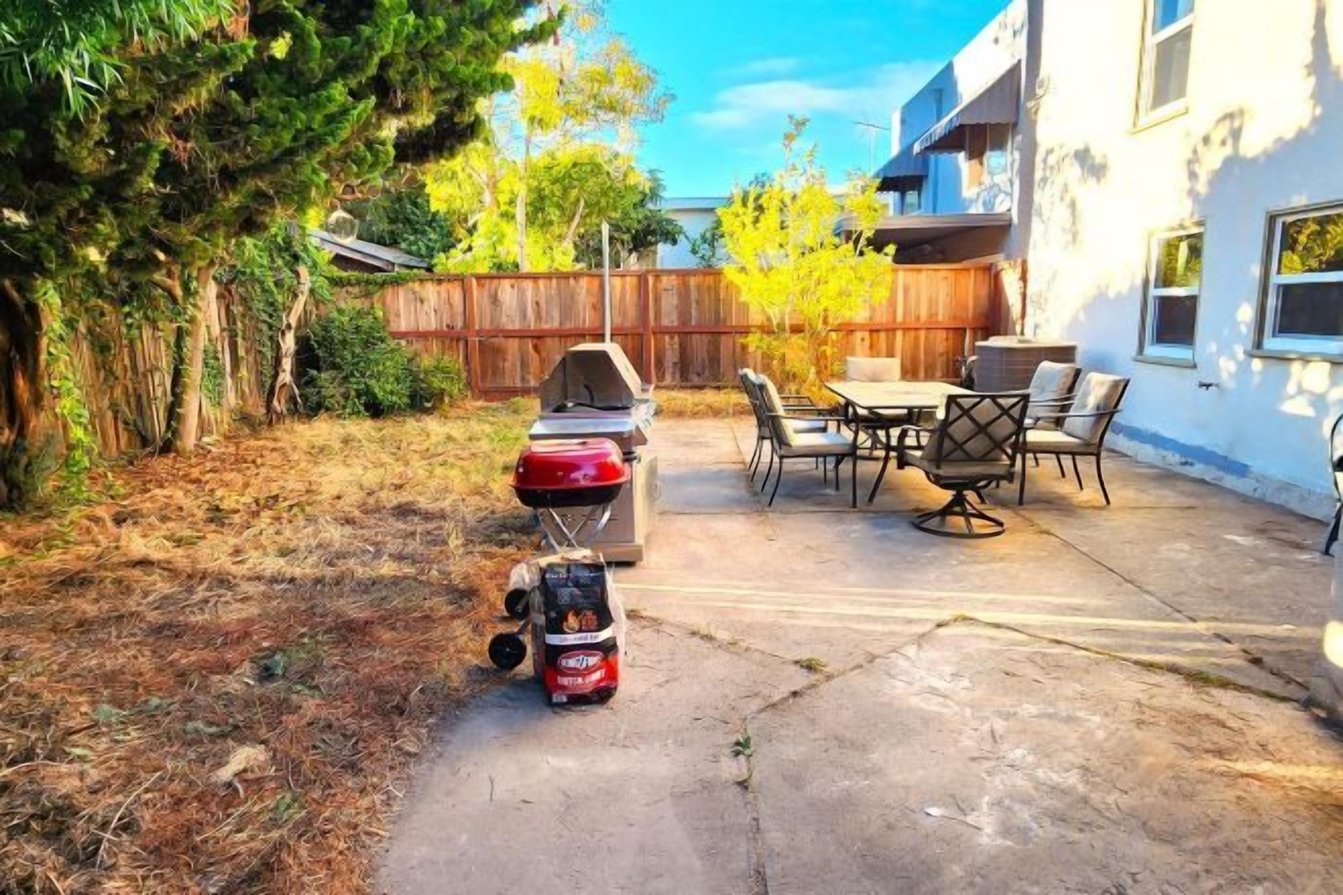 A backyard with a barbecue grill, outdoor furniture, and a concrete patio.