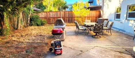 A backyard with a barbecue grill, outdoor furniture, and a concrete patio.