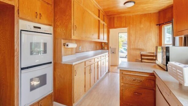 Une cuisine avec des meubles de rangement en bois, un réfrigérateur blanc et un four à micro-ondes.