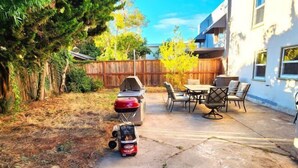 Un jardin avec un barbecue, un petit véhicule et du mobilier d’extérieur.