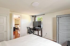 Een slaapkamer met een bed, een bureau, een stoel en een raam.