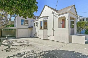 Een tweelaags huis met garage, een overdekte veranda en een klein bijgebouw.