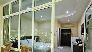 A room with a large window, a wooden table, and a brick wall. - Samran Resort (Chalong)