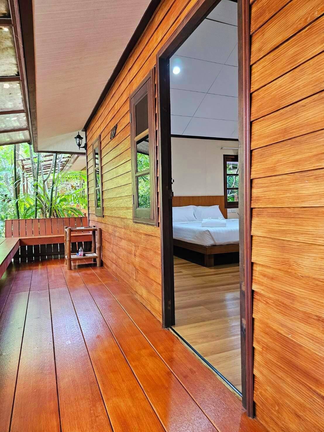 A wooden cabin with a balcony, a bed, and a small table.