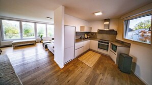 Ett modernt kök med vita skåp, en inbyggd ugn och ett stort fönster som släpper in naturligt ljus.