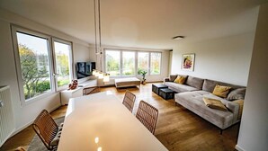 Ett modernt vardagsrum med ett stort matbord, en soffa och en tv.