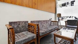 A room with two grey upholstered sofas, a wooden coffee table, and a lamp. - Surya Residency (New Delhi)