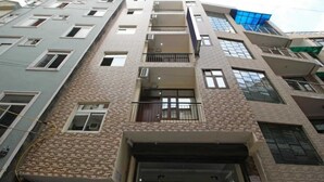 A multi-story building with a brick facade, multiple balconies, and a mix of window styles. - Surya Residency (New Delhi)