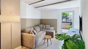 Una sala de estar moderna con un sofá seccional, una mesita redonda y una planta grande.