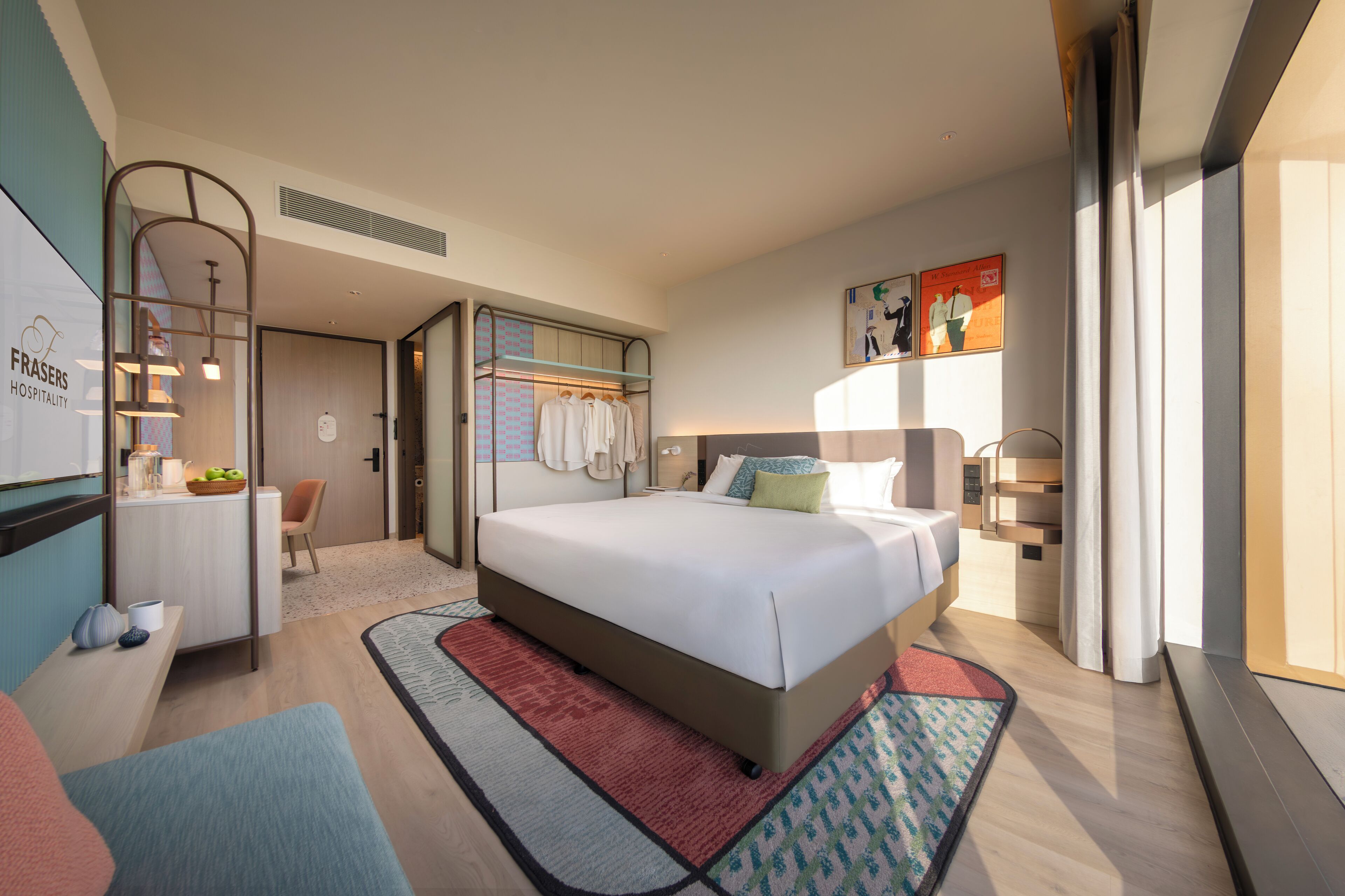 A modern hotel room with a large bed, bedside tables, a desk, and a wardrobe.