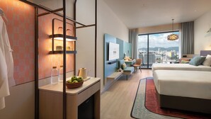 A modern hotel room with a large bed, a desk with a computer, a TV, and a city view. - Capri by Fraser Penang (George Town)
