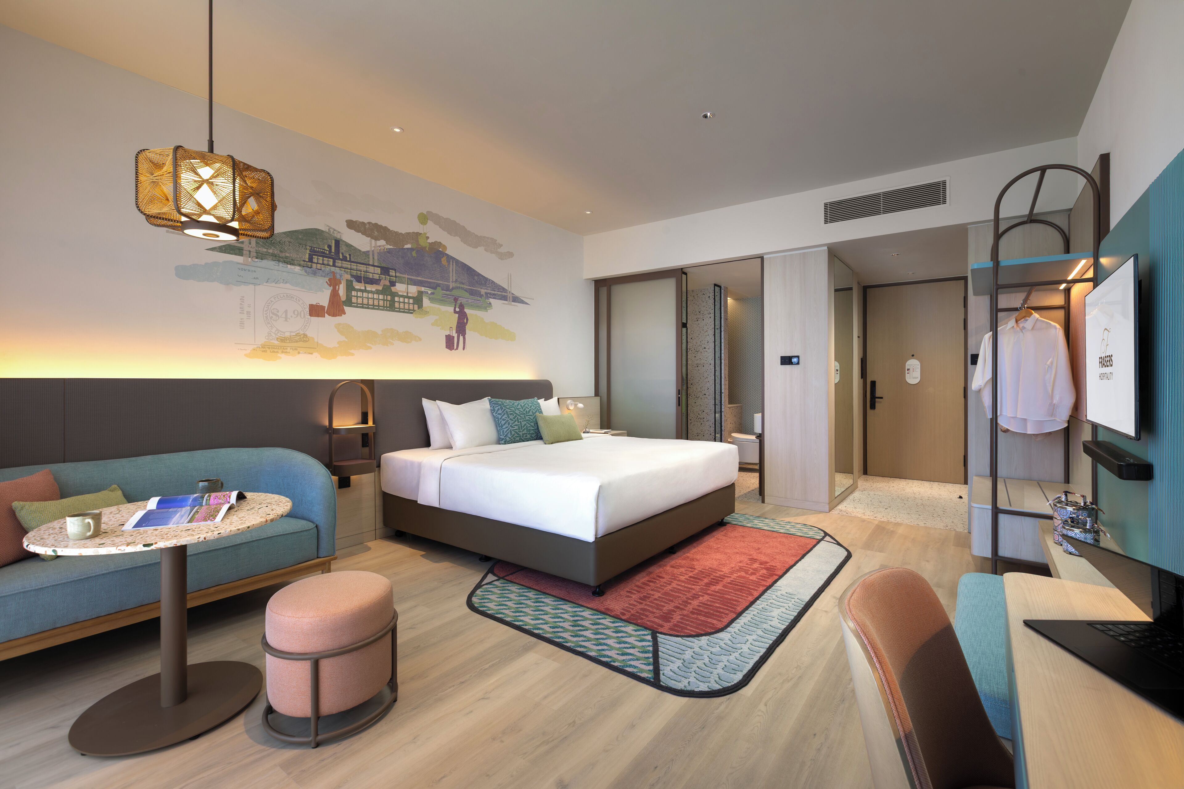 Ett modernt hotellrum med en säng, en soffa, ett skrivbord och en hängande lampa.