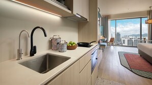 A modern kitchen with a stainless steel sink, a black faucet, and a bowl of green apples on the counter. - Capri by Fraser Penang (George Town)