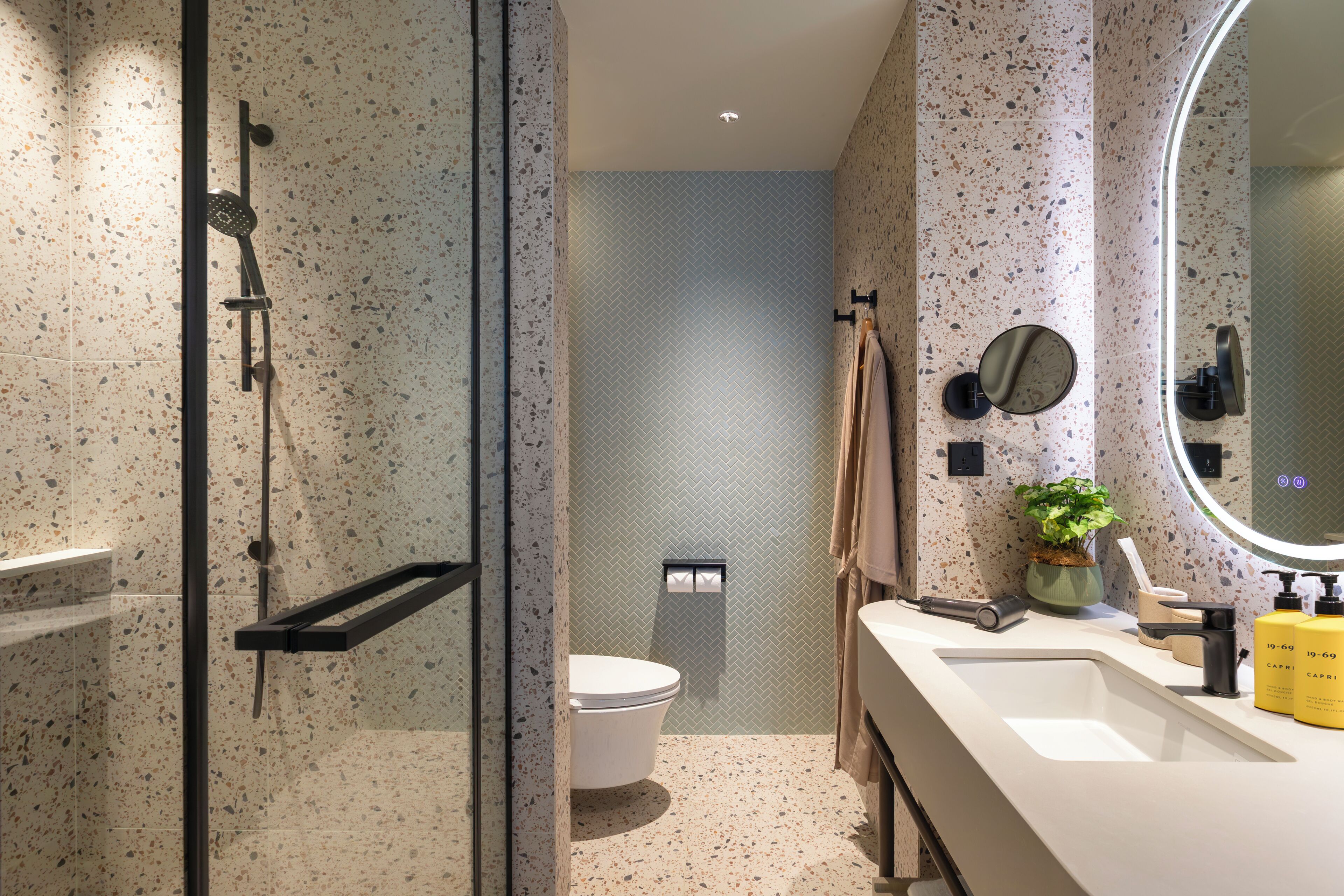 A modern bathroom with a shower, toilet, and sink.