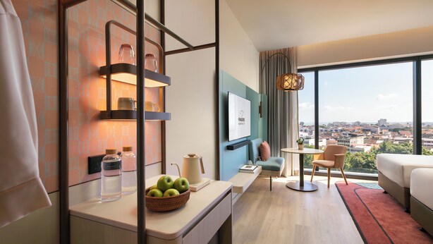 A modern hotel room with a city view, a dining area, and a cozy seating space. - Capri by Fraser Penang (George Town)