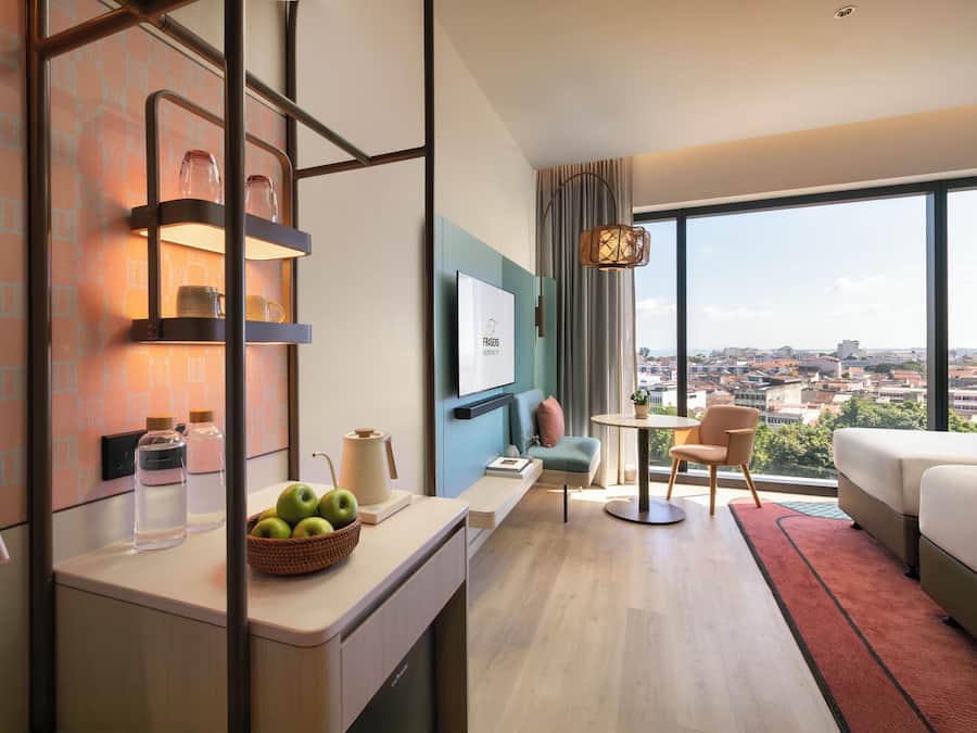A modern hotel room with a city view, a dining area, and a cozy seating space.